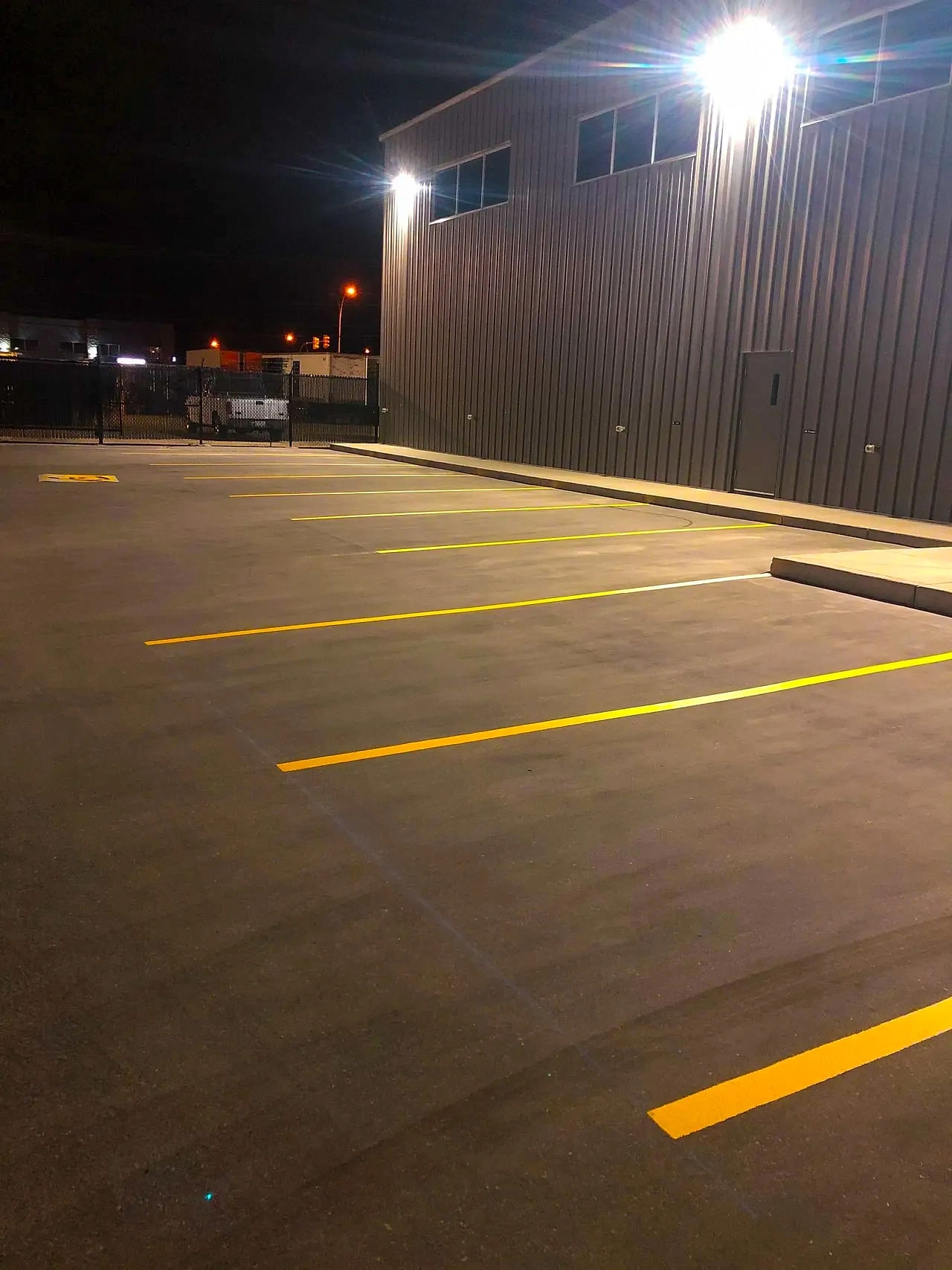 Freshly painted yellow parking stall lines on new black asphalt outside a commercial building
